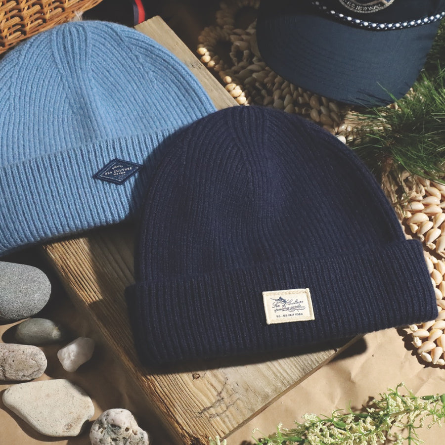Light blue and navy knit beanies on a wooden board