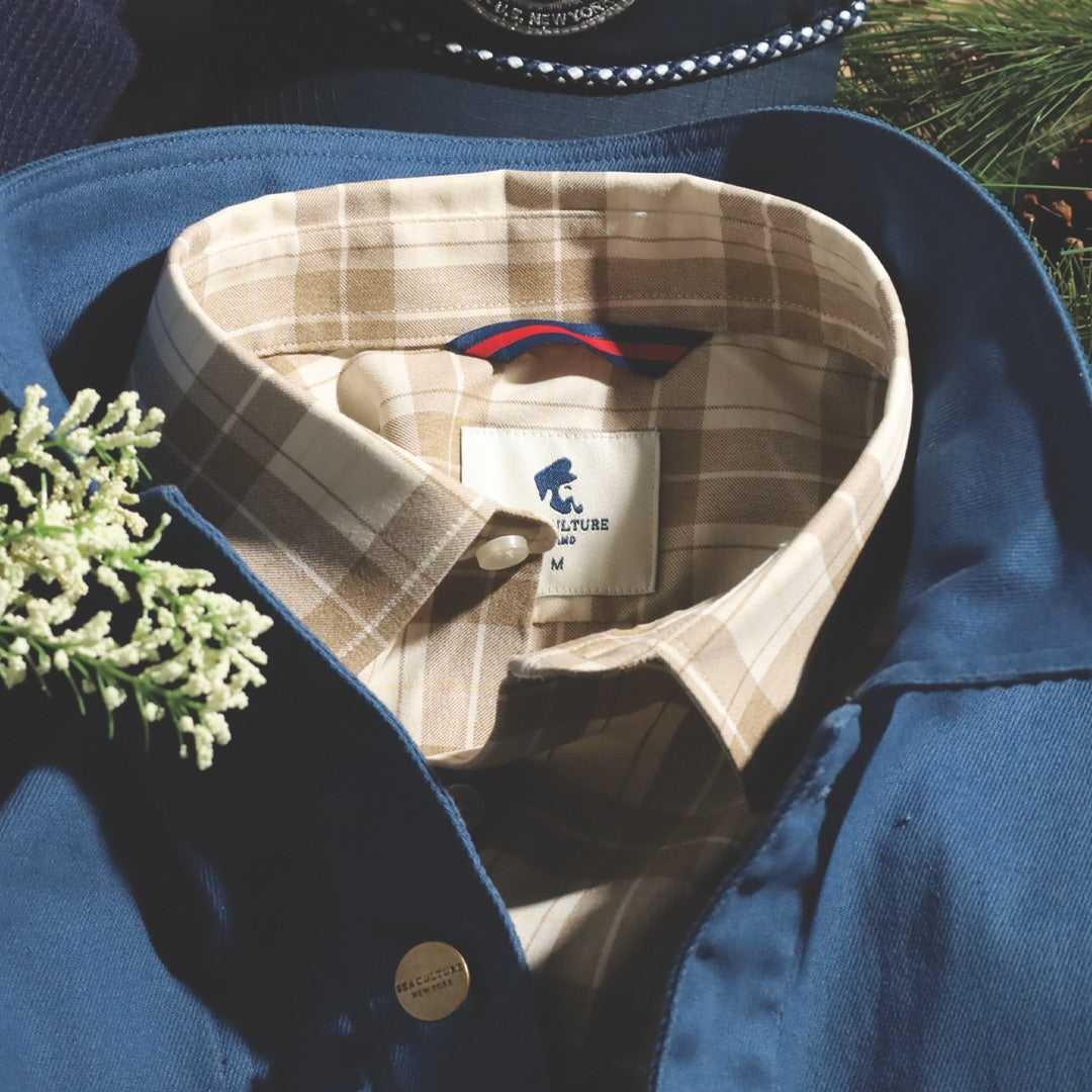Plaid shirt layered with a blue jacket and navy cap