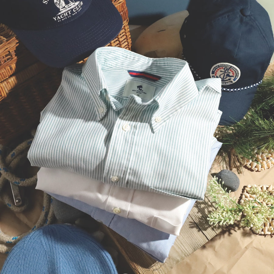 Folded green stripe, white and blue Oxford shirts with navy caps